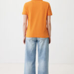 Dos d’une personne en polo orange et jean large clair