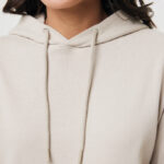 Femme souriante portant un sweat à capuche beige