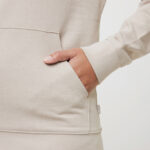 Main dans la poche d’un sweat beige