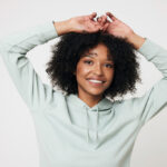 Jeune femme souriante aux cheveux bouclés, bras levés