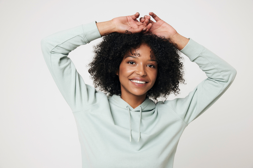 Jeune femme souriante aux cheveux bouclés, bras levés