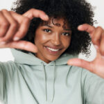 Femme souriante cadrant avec ses doigts