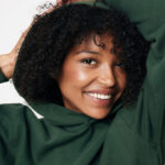 Femme souriante en sweat vert, cheveux bouclés