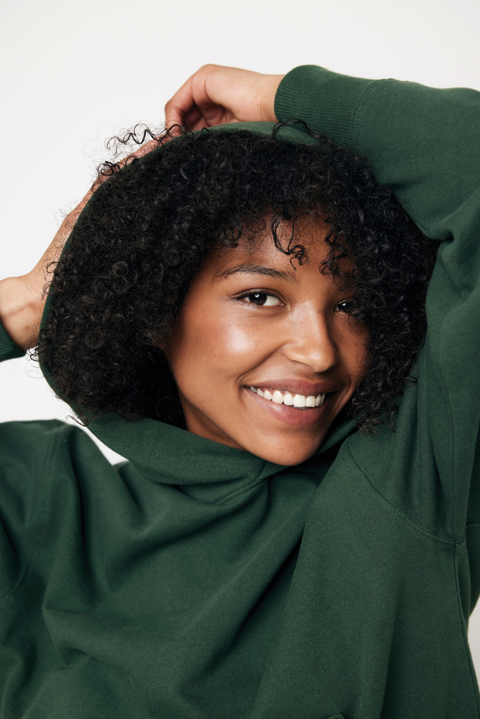 Femme souriante en sweat vert, cheveux bouclés