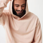 Homme souriant en hoodie beige, fond neutre